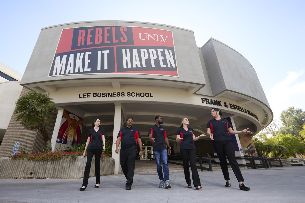 four people talking and walking out of a building