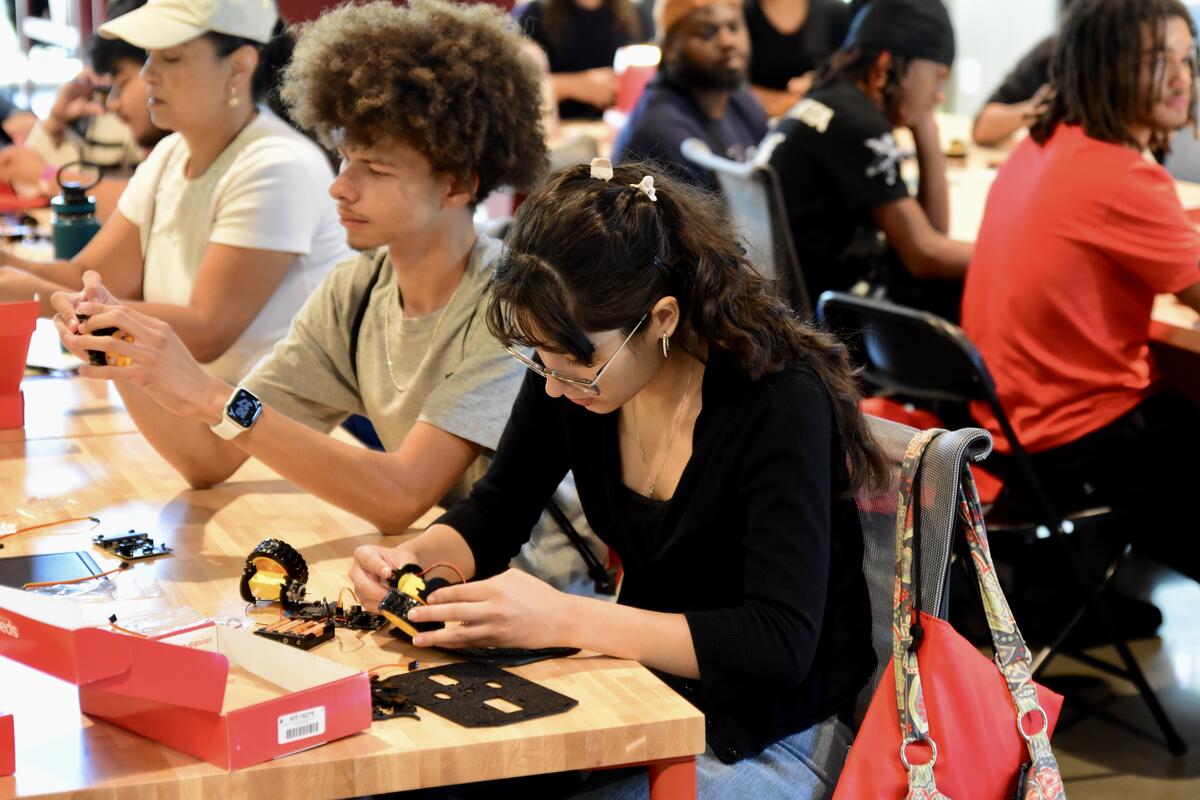 Students sitting at a long table working on robots