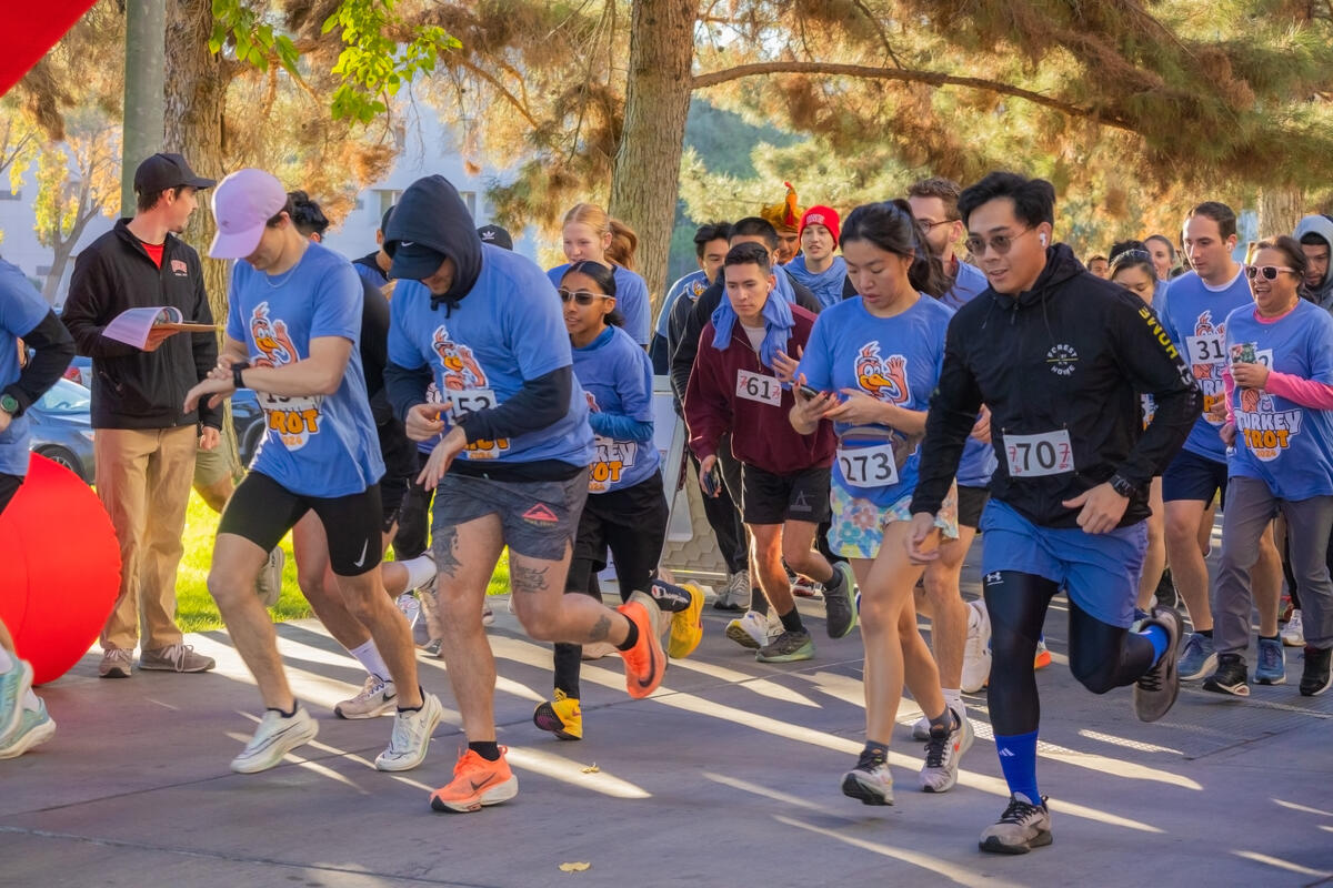 A group of people wearing purple shirts saying "Turkey Trot" running
