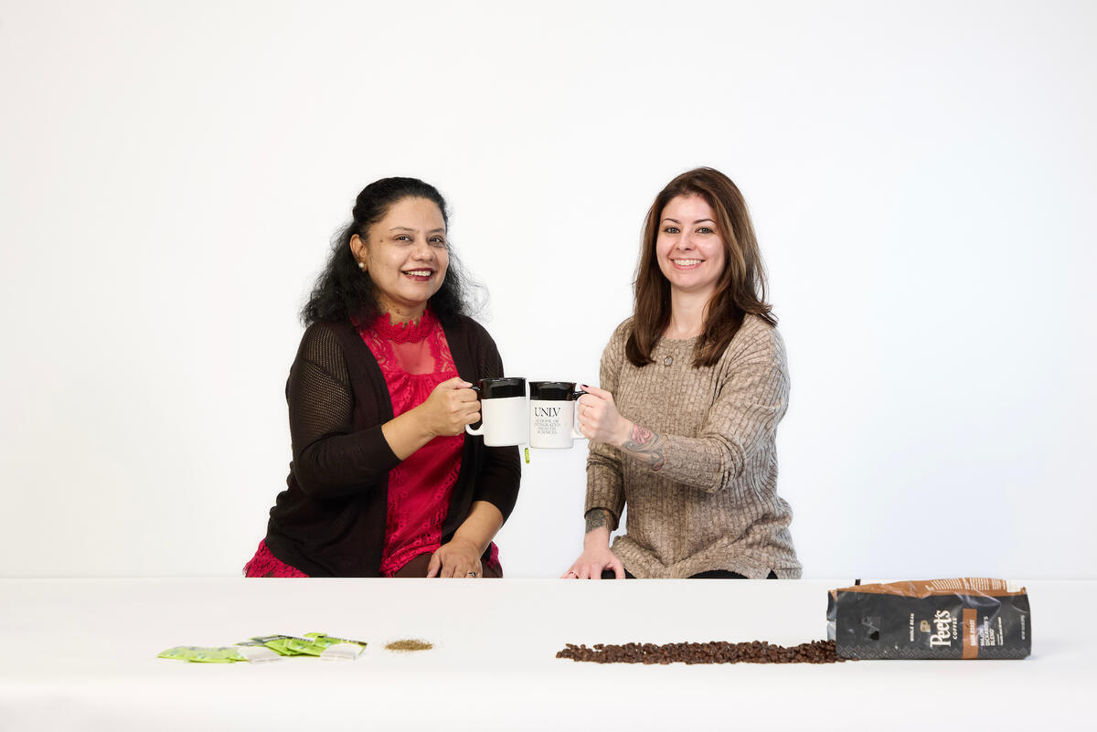 two professors holding up tea and coffee