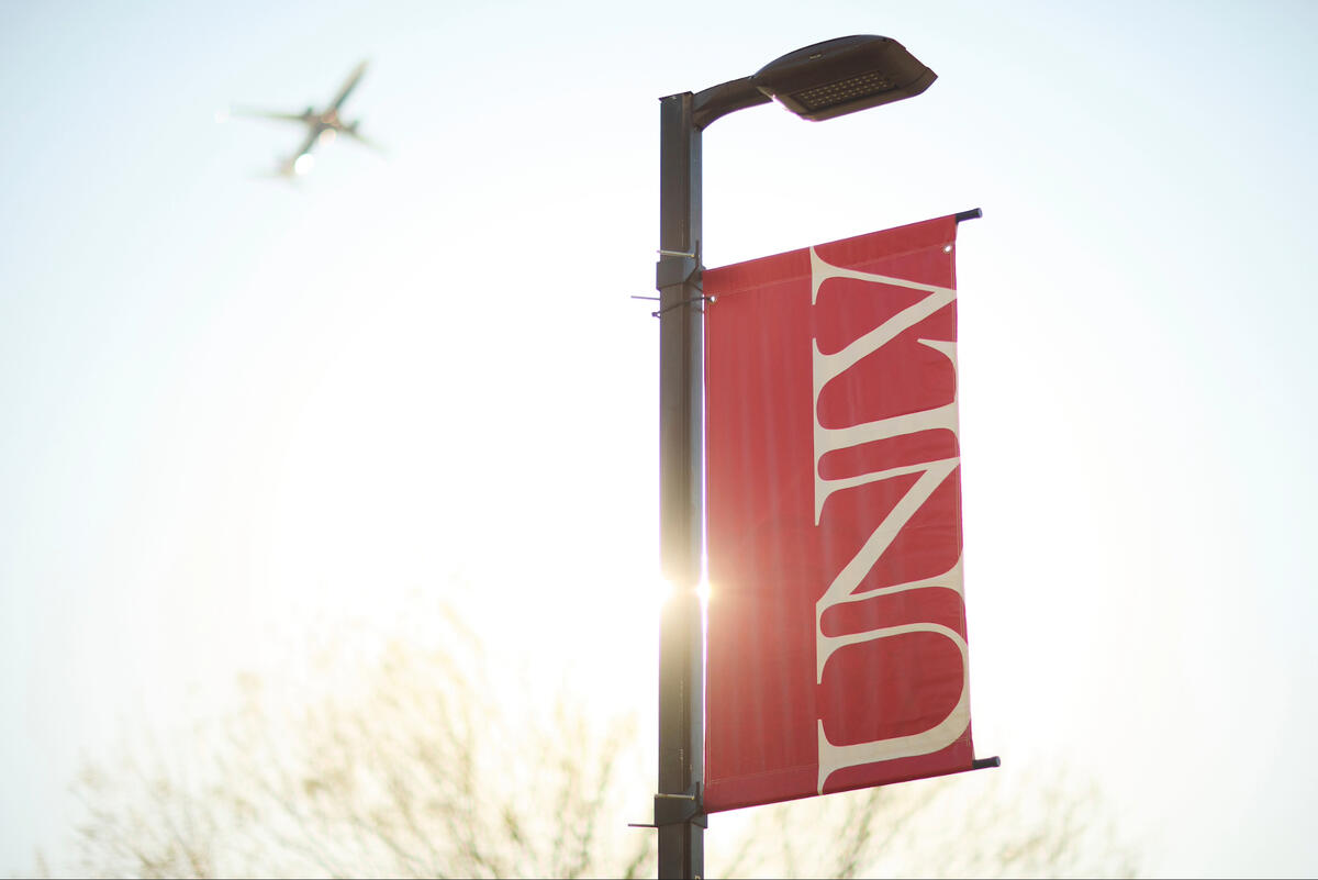 A red banner with the UNLV logo. Above, a plane flies.