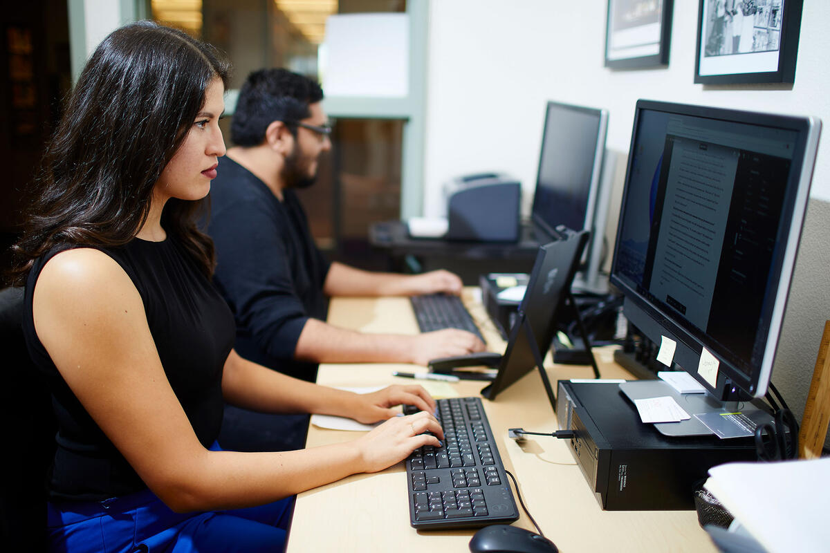 Two people working at computers in an office setting.