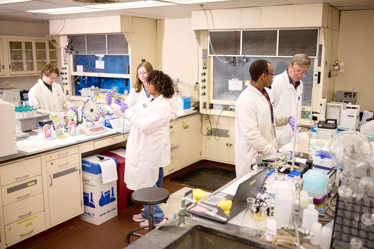 Researchers wearing lab coats working in a radiochemistry laboratory.