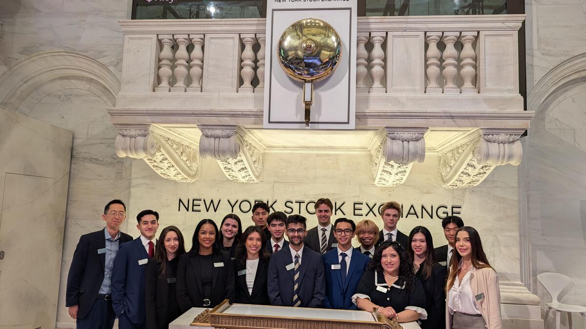 A group of students poses in front of the New York Stock Exchange building.