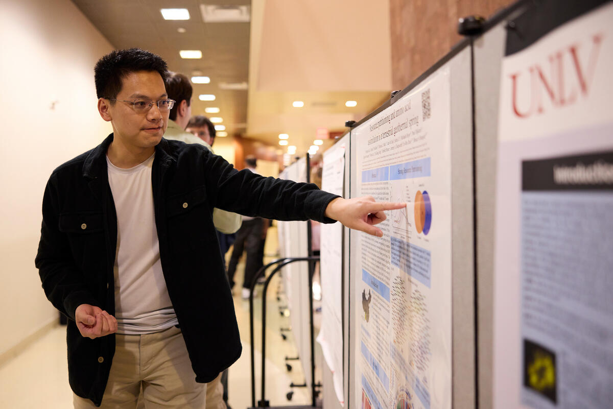 A student pointing to a poster board as he presents