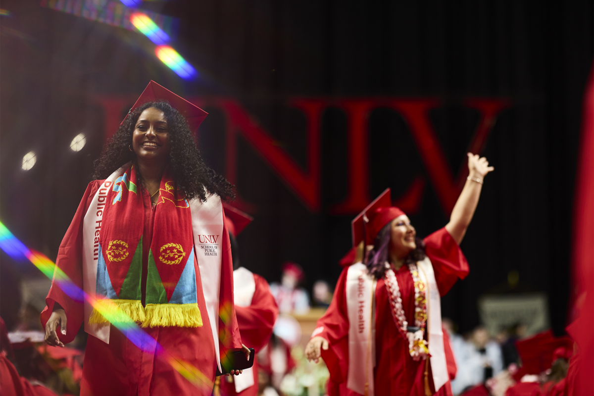 Students walking and waving at a graduation ceremony