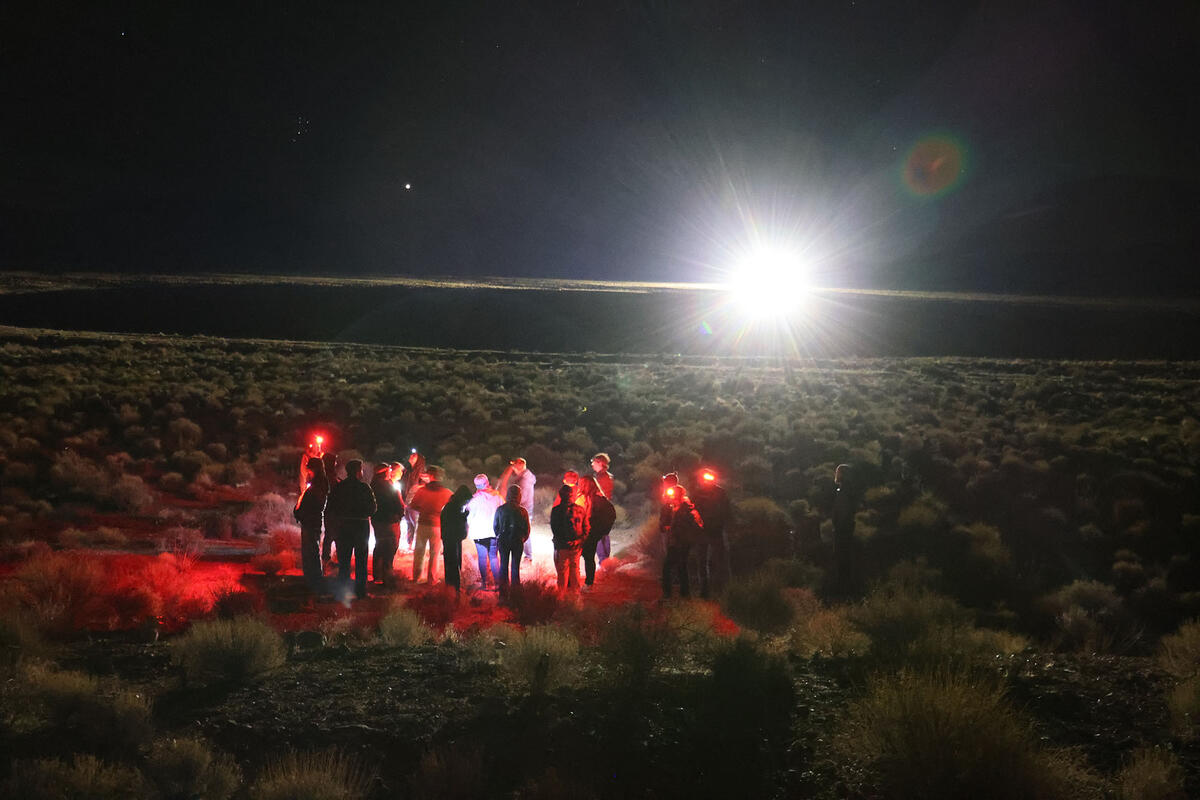 large group of people in remote desert location at night with red headlamps