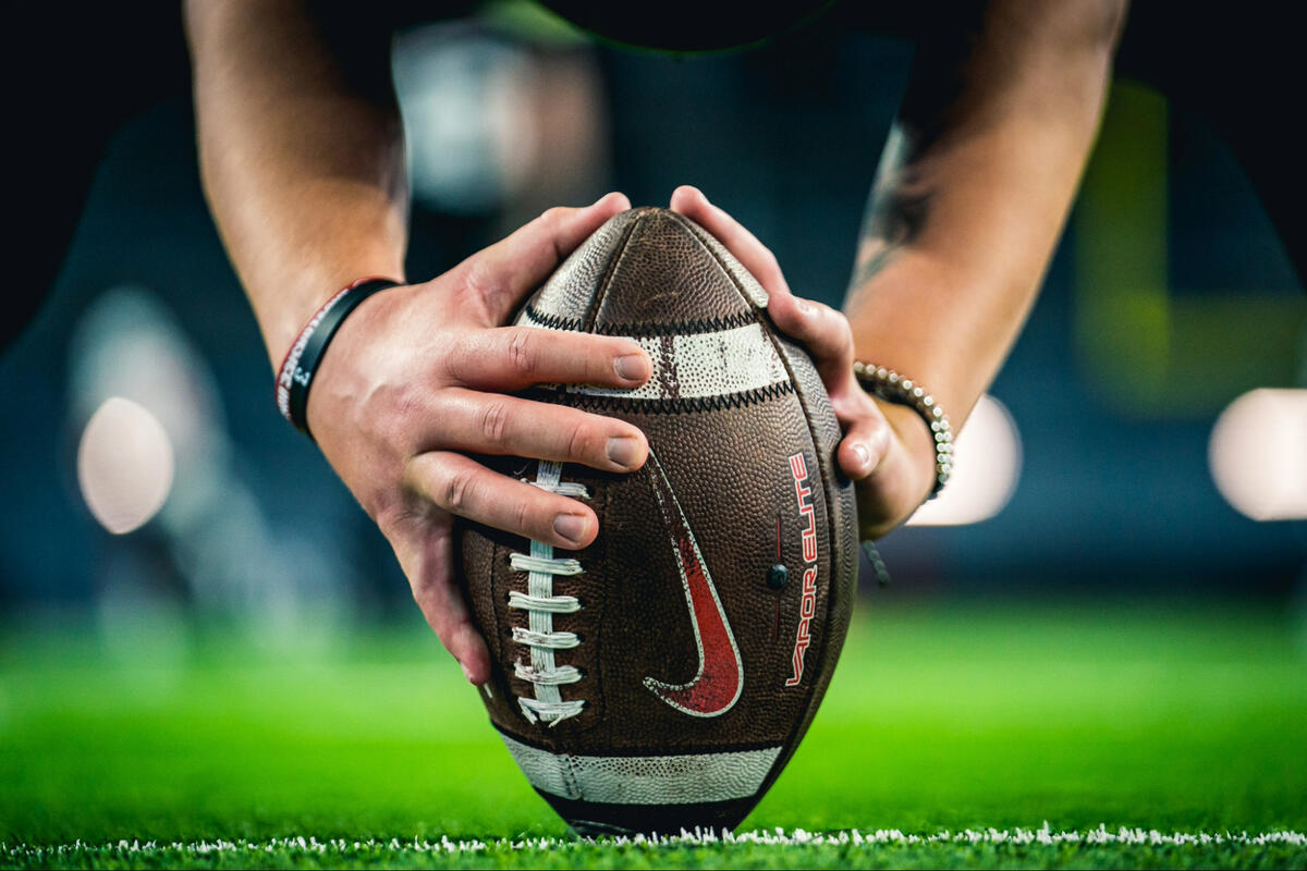 A closeup of a football between a football player's hands.