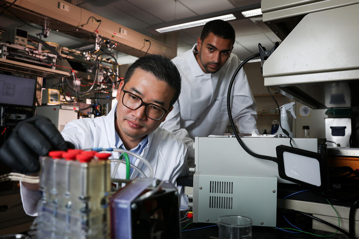 Two researchers in white lab coats working with laboratory equipment.