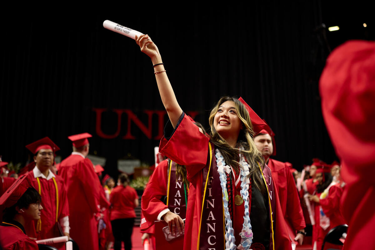 Student waving a diploma during a graduation ceremony