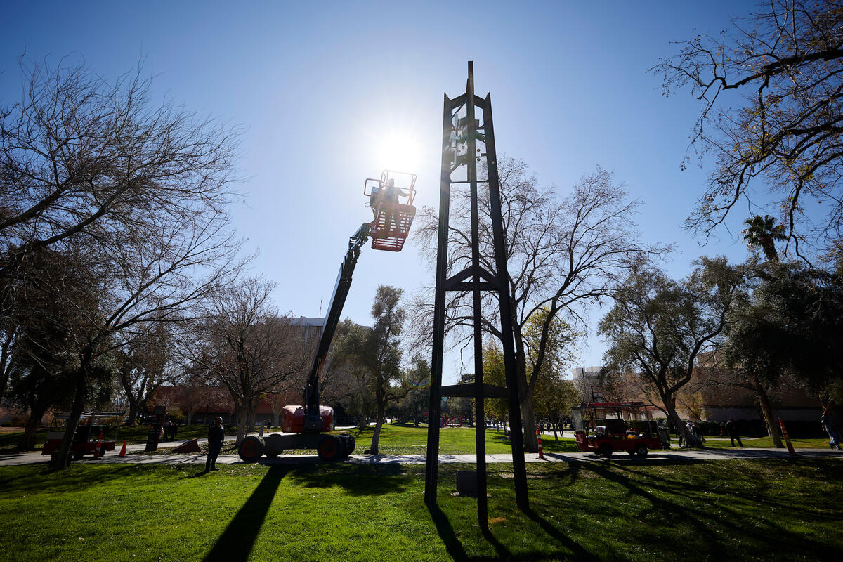 man in cherry picker adjusts hands of clock tower