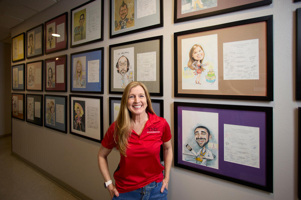 Wendee Johns in front of wall of student caricatures
