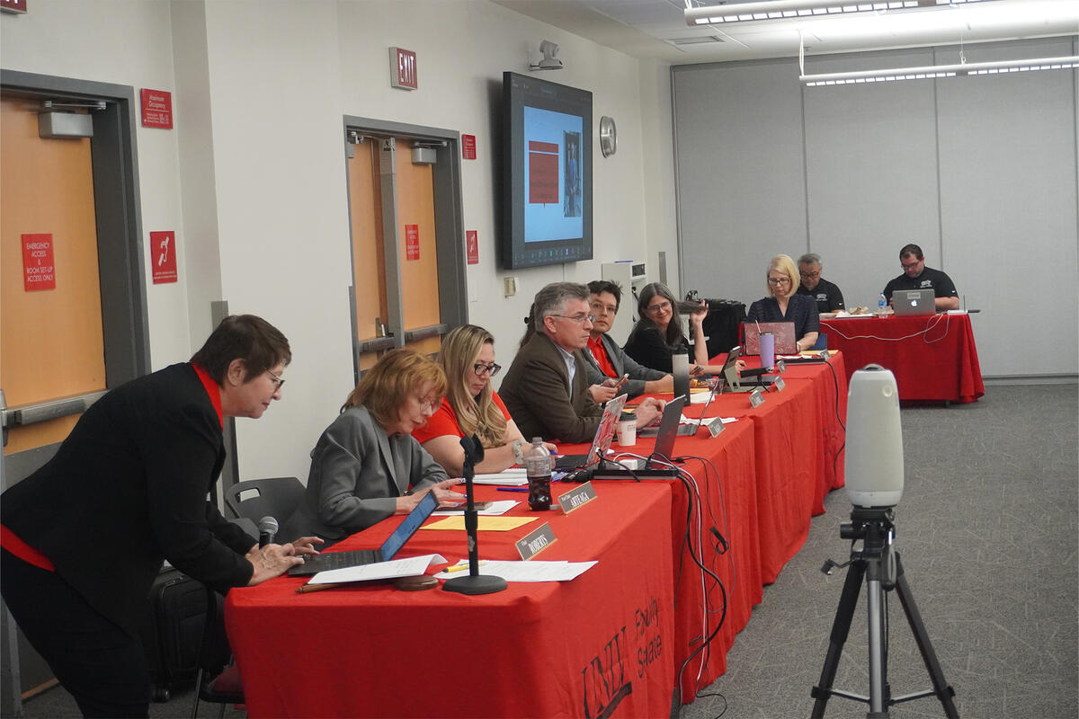 Faculty Senate members sitting at a long table in front of a meeting room
