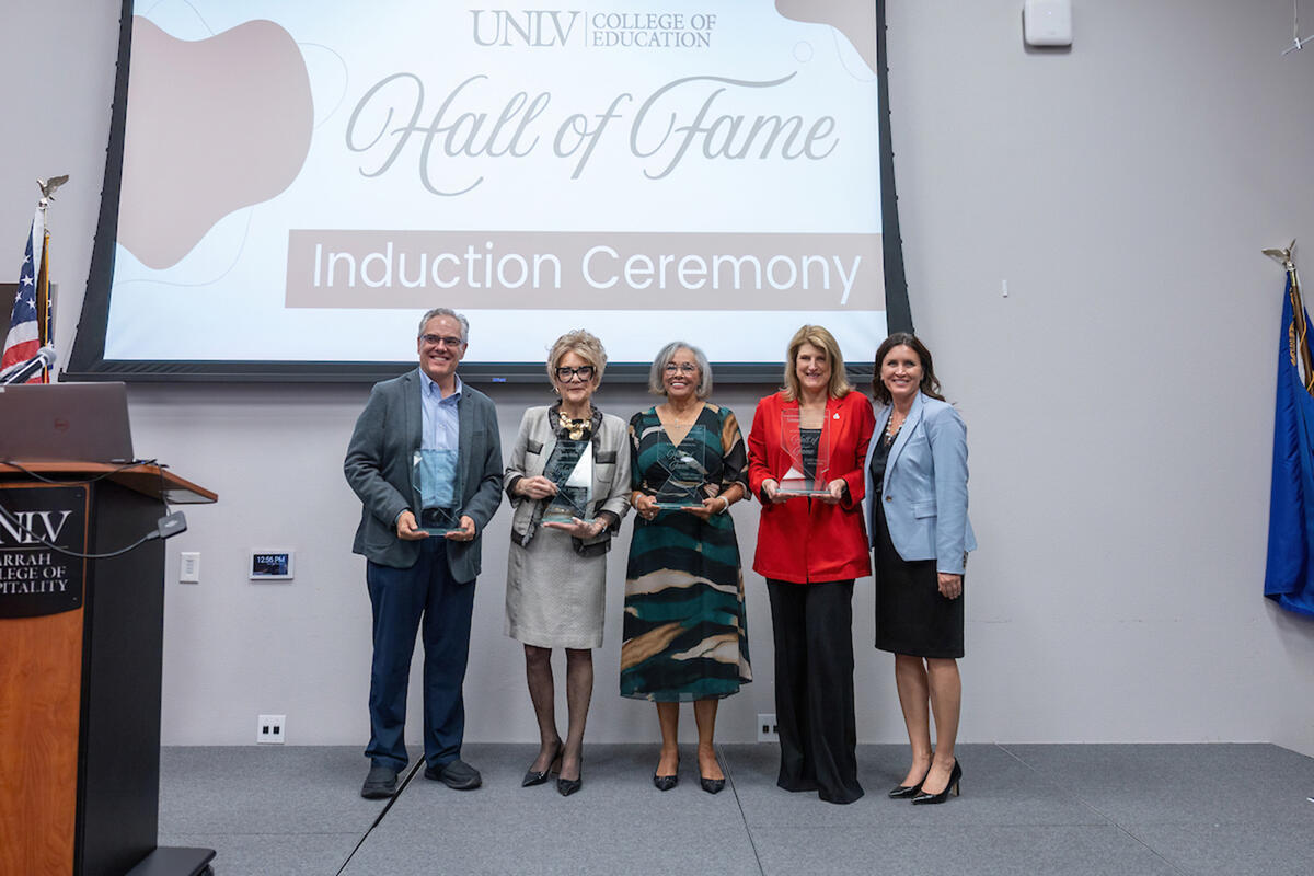 Five award recipients stand on a stage.