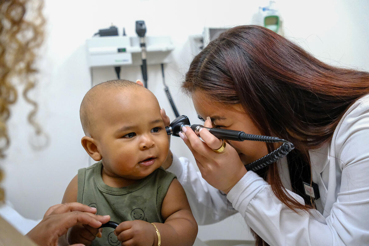 A doctor uses an otoscope to examine a baby’s ear.