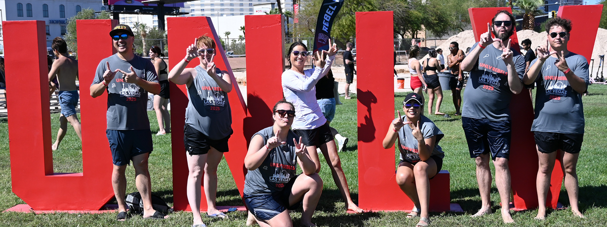 People standing by a sign that says "U-N-L-V"