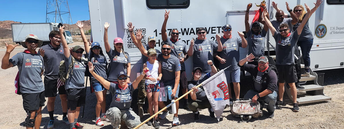 Group of people, smiling and raising their arms in front of a Vet Center van