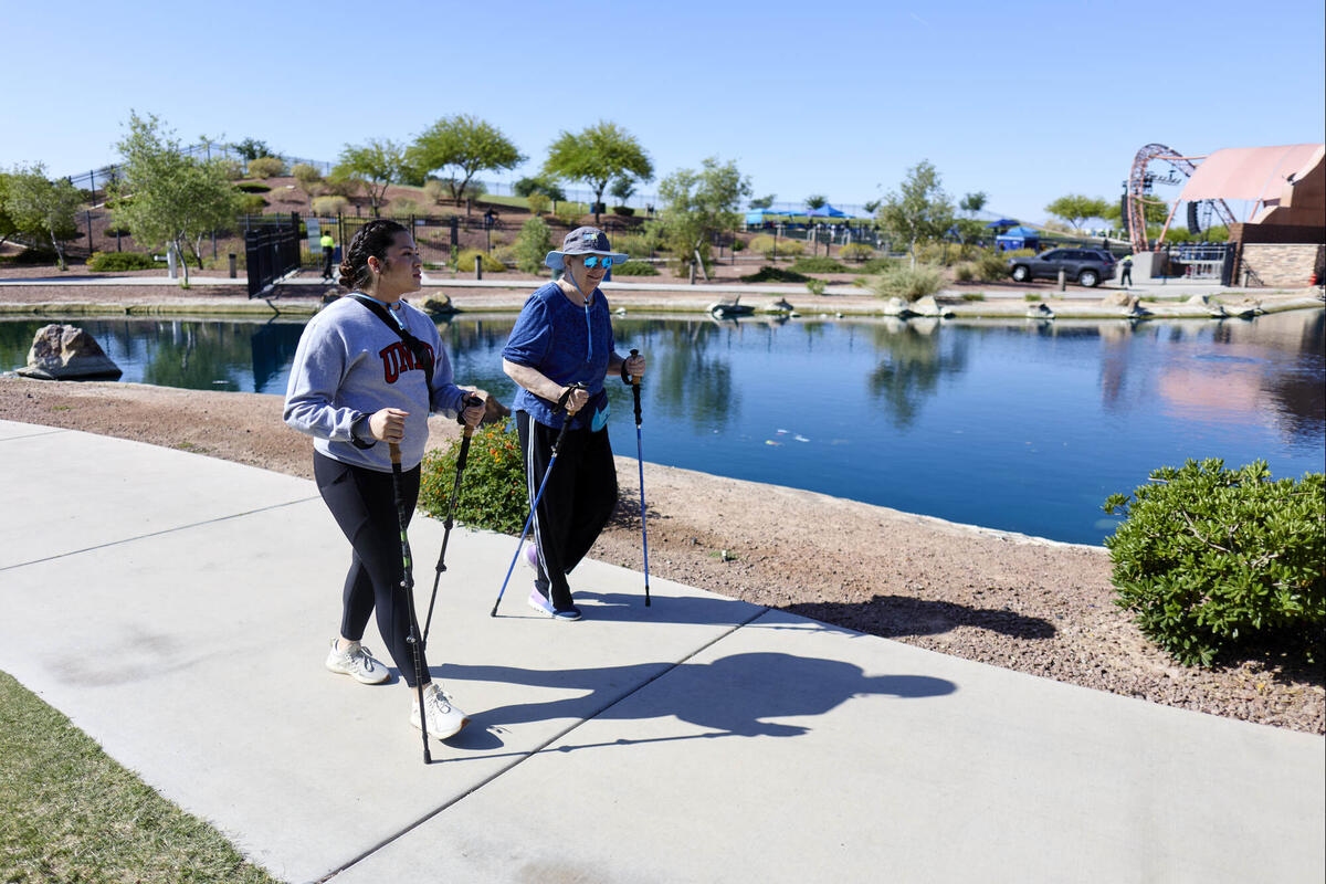 two people walking using tools for assistance by water