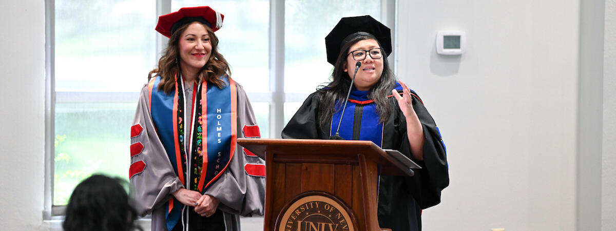 Two faculty members in academic regalia standing at a podium.