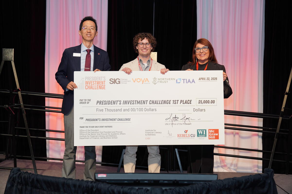 3 people standing on a stage holding a large check