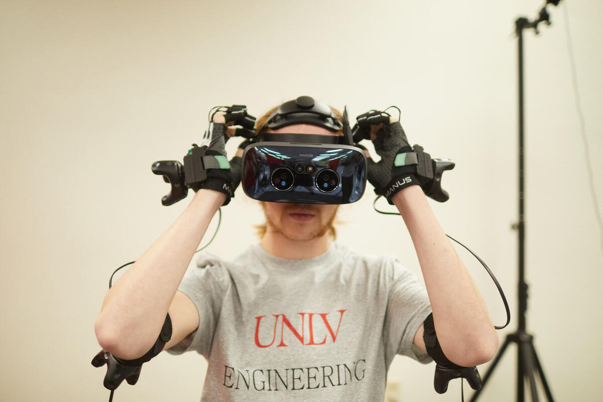A man in a white room with a headset on his head and a pair of gloves