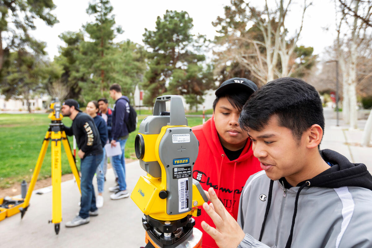 Two students using a surveying tool for an engineering course