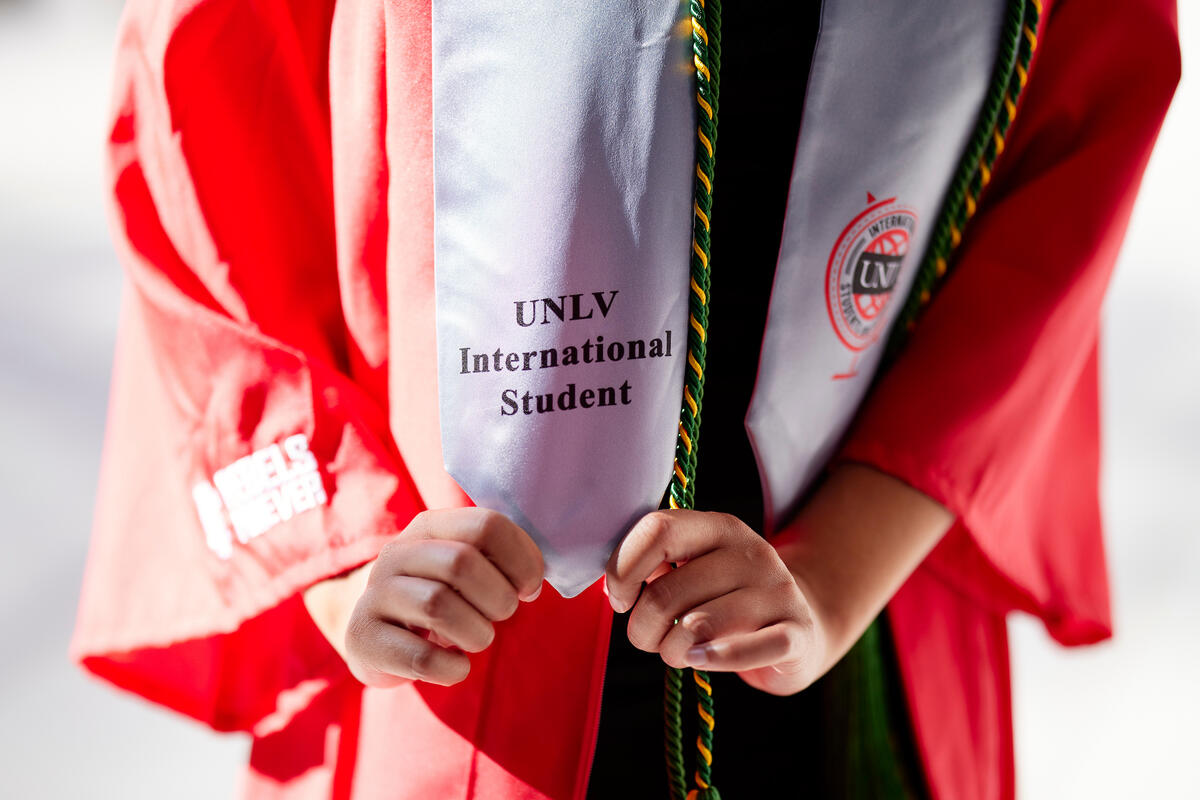Student showing off their "UNLV International Student" graduation stoll