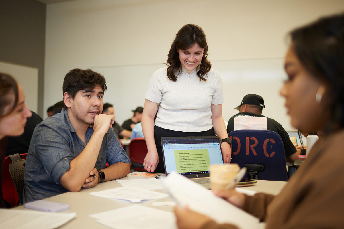 Instructor talking with students around a table.