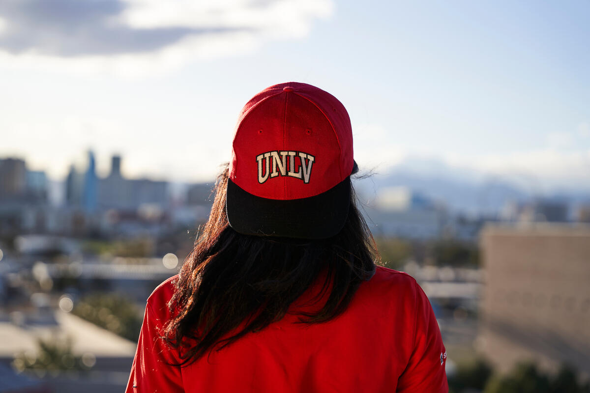 Student with a UNLV hat looking out to a view of the Las Vegas Strip