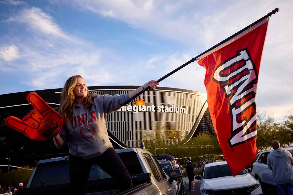 Photo of a student celebrating infront of a stadium waving a flag