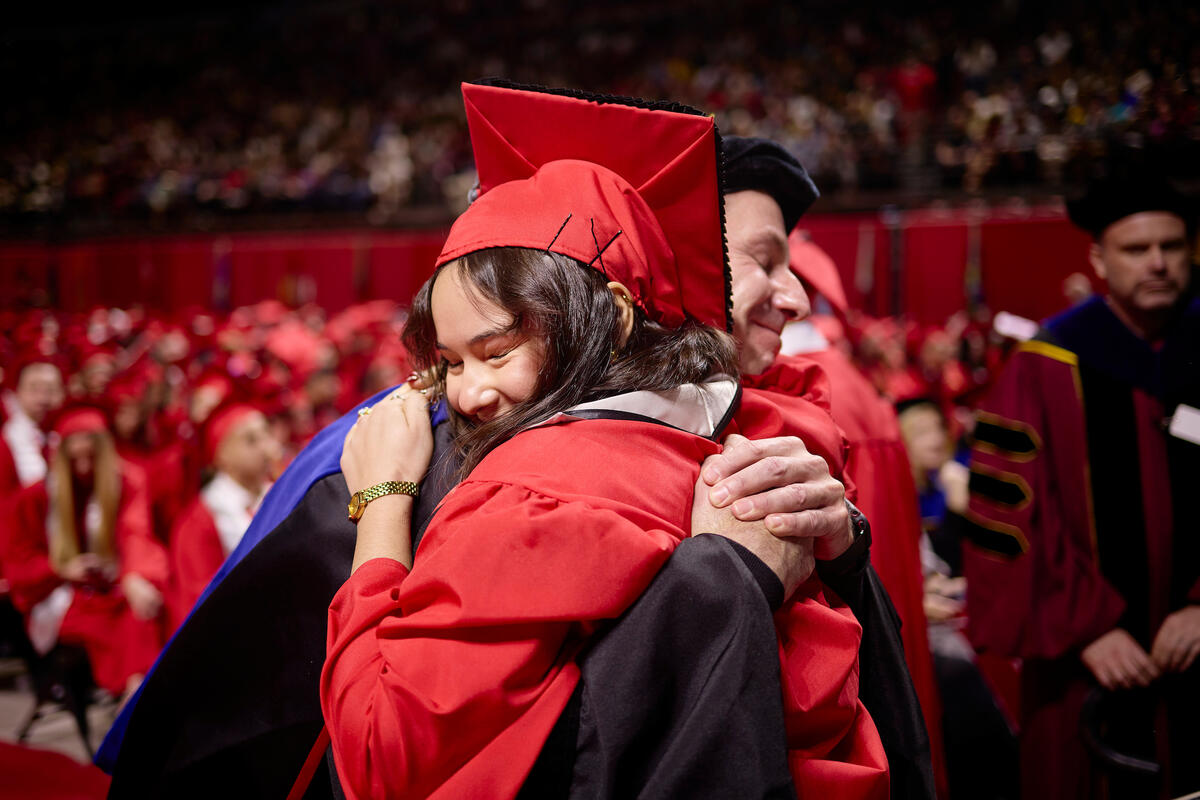 Graduating student hugging a faculty member at commencement