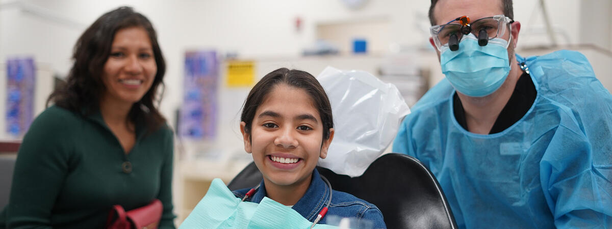 A woman, a child, and a dental resident smiling