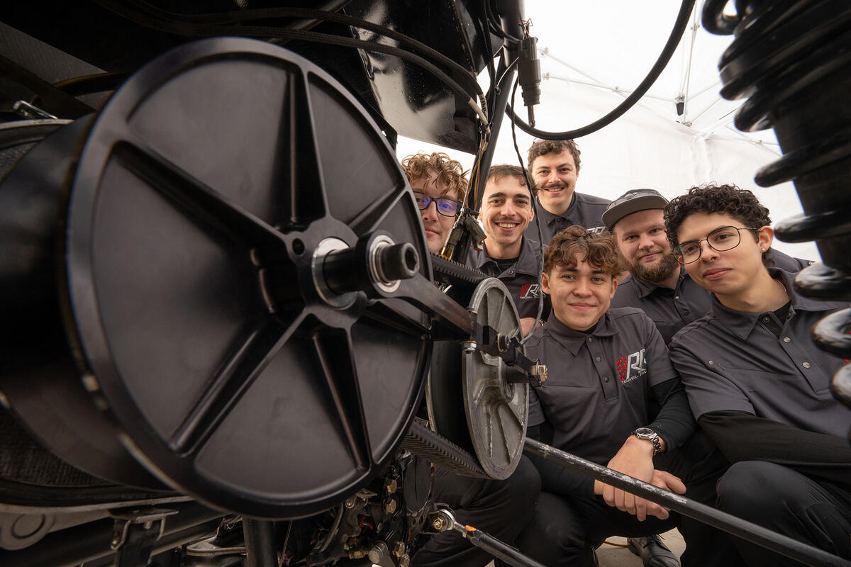 A group of people taking a photo with a gear like tool