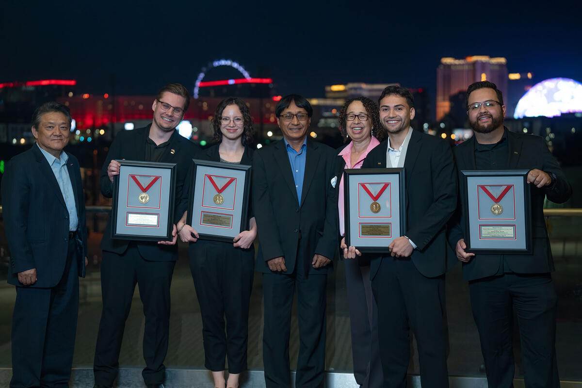 People holding award plaques with a medal inside