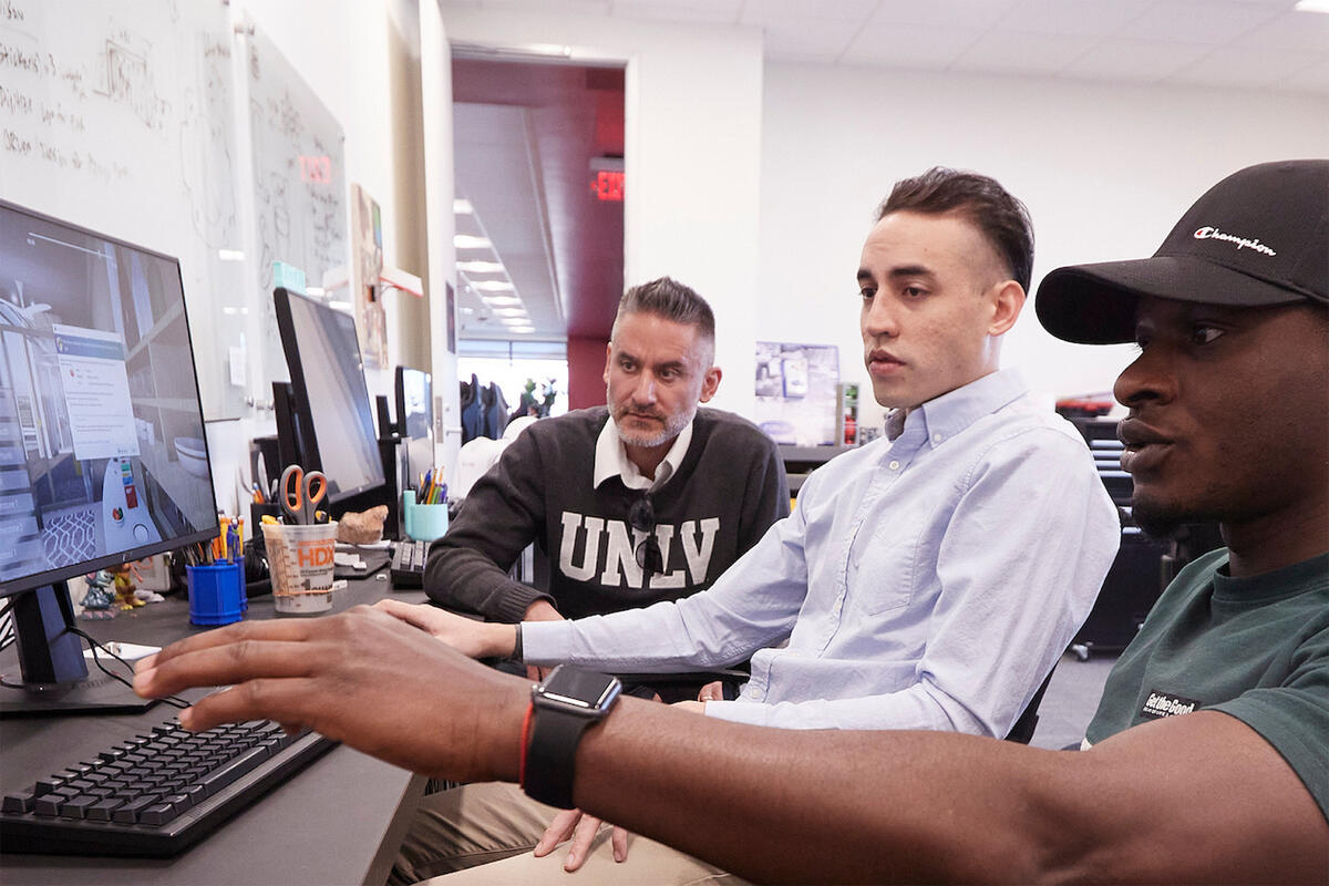 Students and an instructor sitting down at a computer lab.