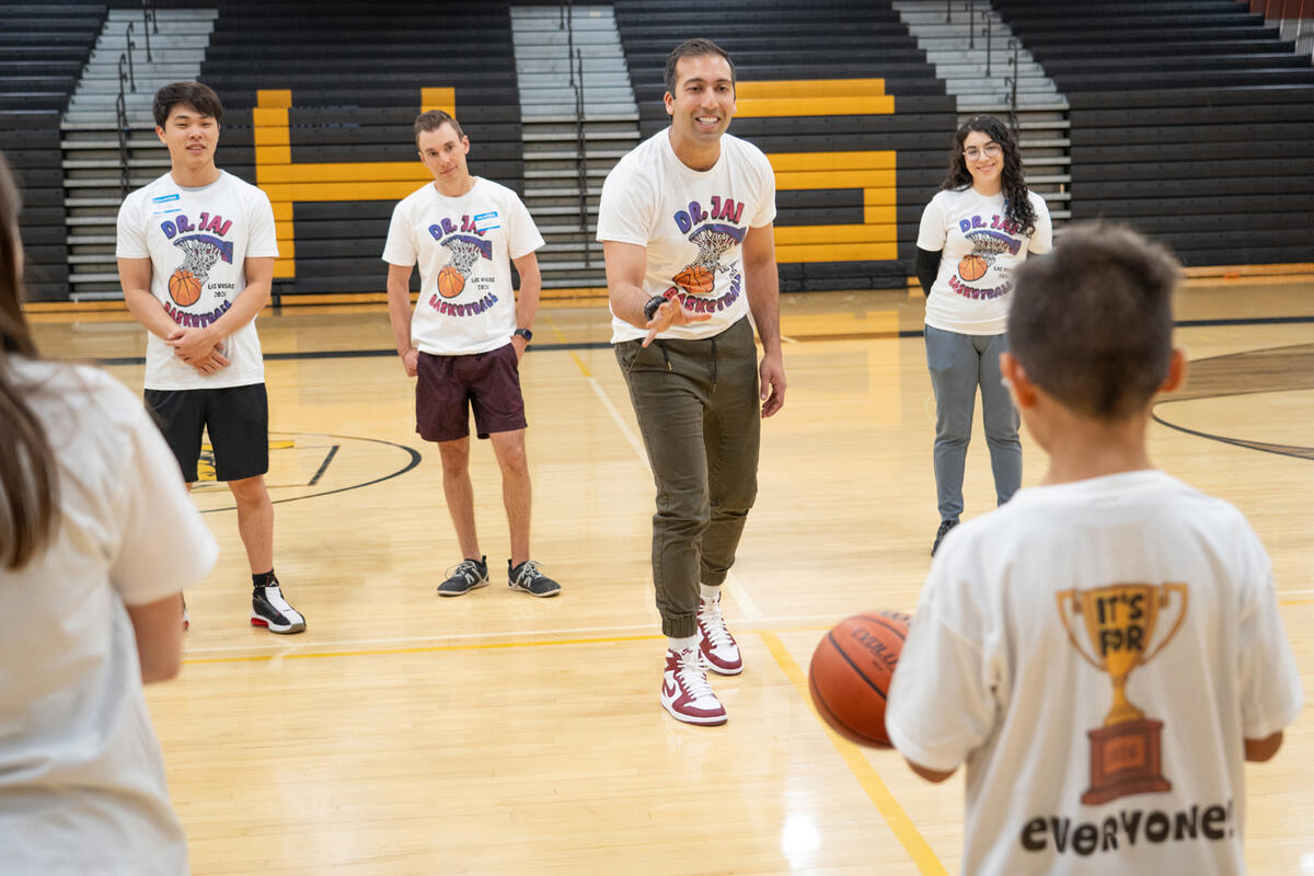 Dr. Jaineet Chhabra and medical students playing basketball with community youth during the “Dr. Jai Basketball: It’s for Everyone!” camp at the Ed W. Clark High School gym.