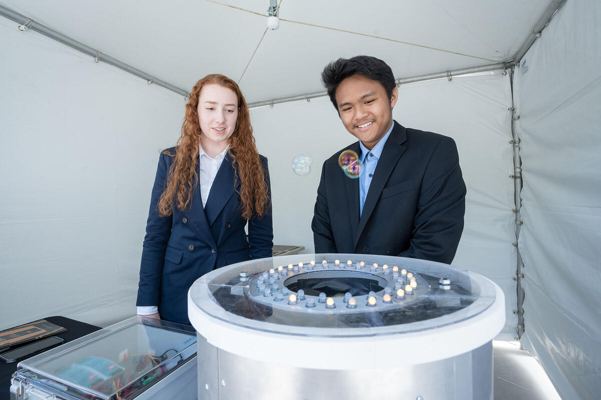 Two people looking at a amachine that is producing bubbles 