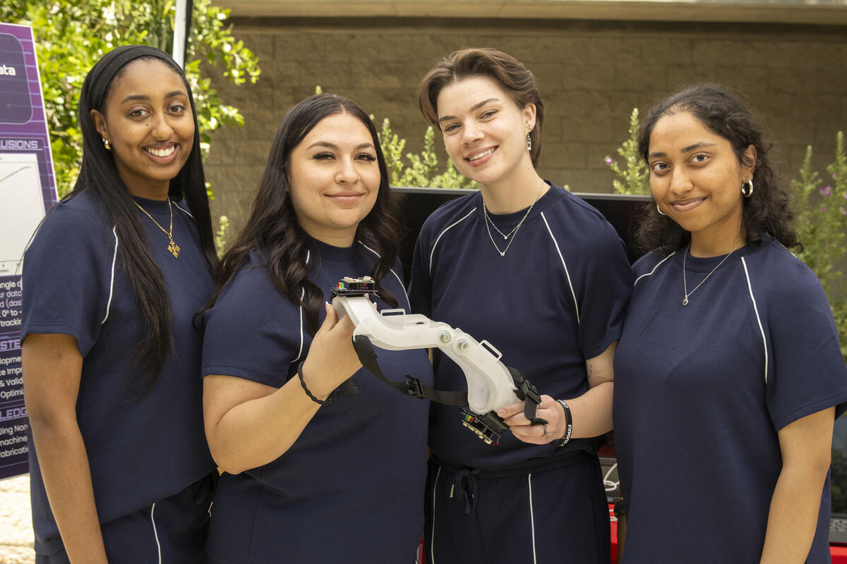 Four people wearing navy blue scribes holding a mechanical tool 