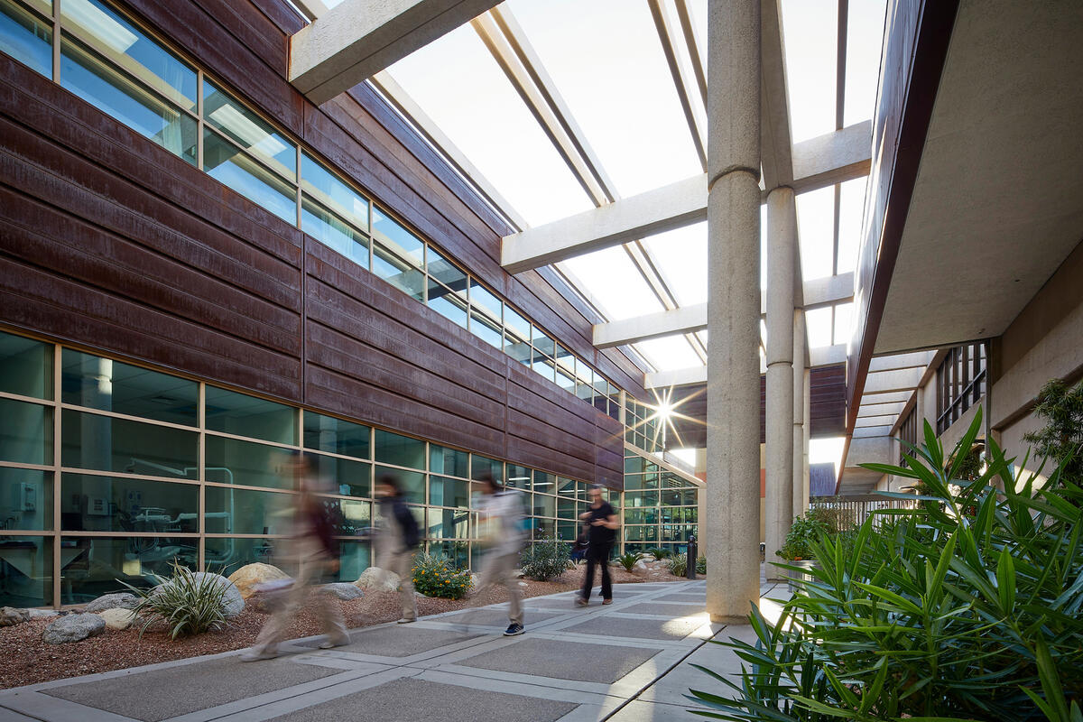 Students walk through a courtyard between buildings with large windows