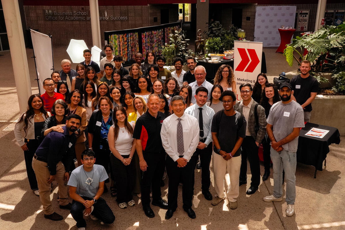 A group photo of students and faculty in the Lee Business School atrium