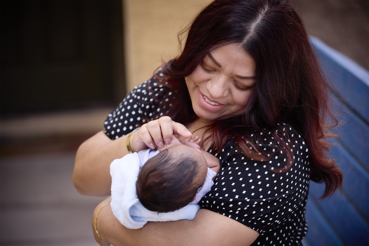 A woman in a black shirt with white dots cradling a baby