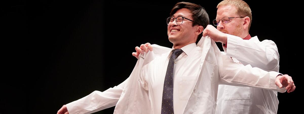 Student receives doctor's jacket at white coat ceremony