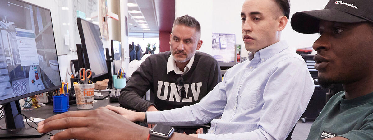 Students and an instructor sitting down at a computer lab.