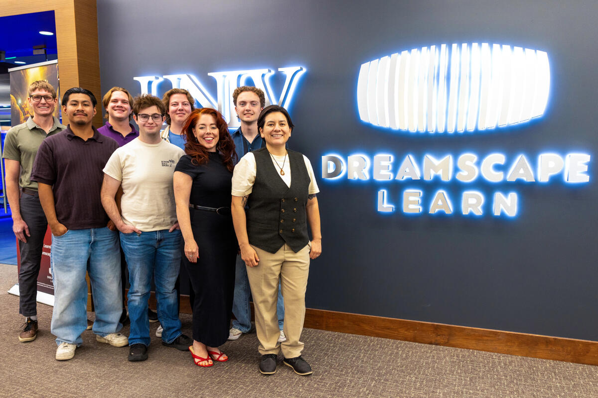 A group of students and faculty stand next to the Dreamscape Learn signage in the Lied Library