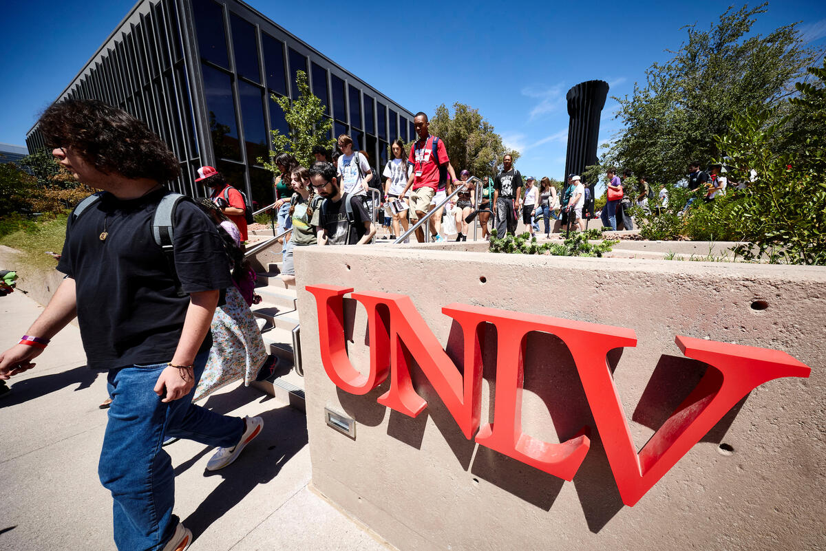 students walking down stairs past UNLV signage, with the Flashlight sculpture in the background