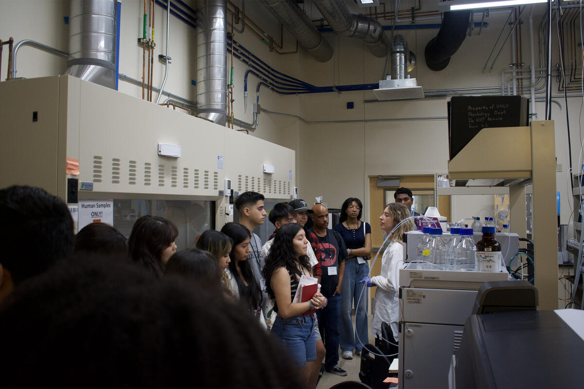 Group of people on a tour in a chemistry lab with main speaker in lab coat.