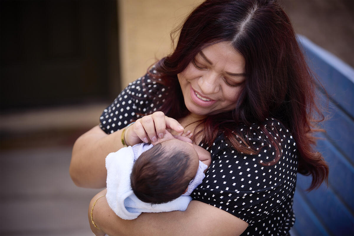 A woman in a black shirt with white dots cradling a baby