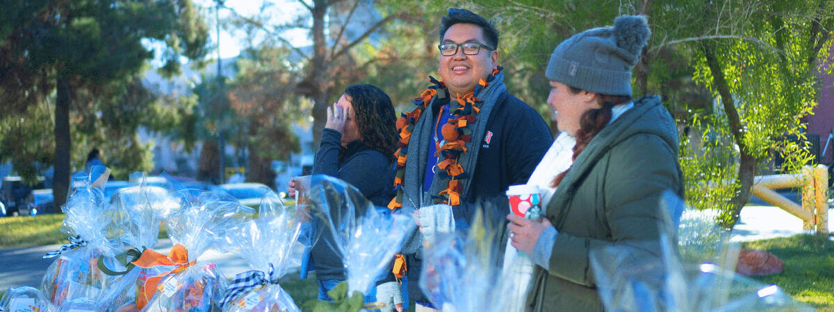 Three people standing by a table with gift baskets