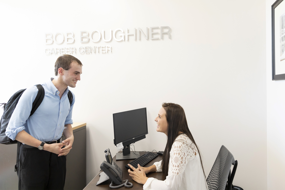 A person talking to someone sitting at a desk