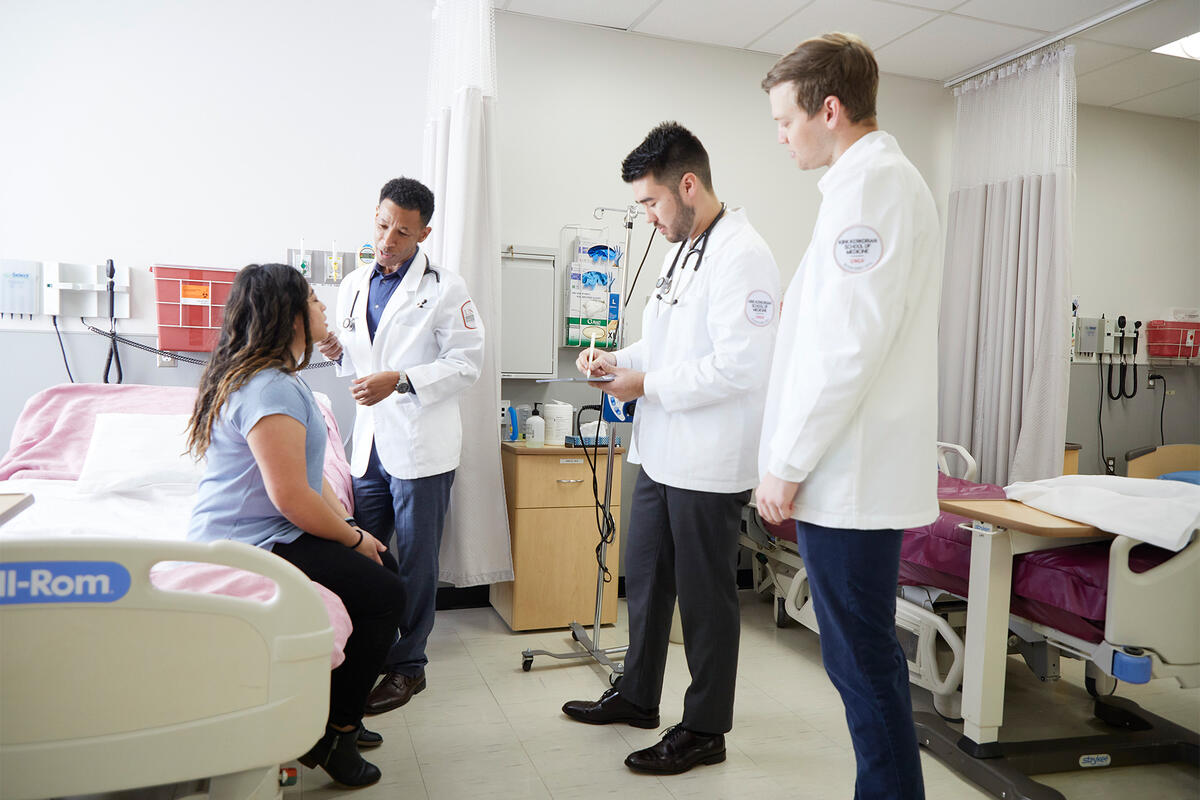 A doctor with two medical students speaking to a patient
